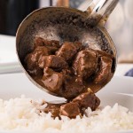 Pouring Steak and gravy over the rice.