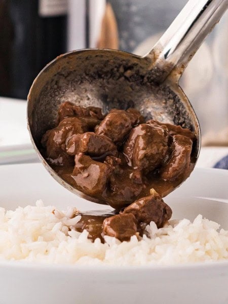Pouring Steak and gravy over the rice.