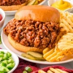 Closeup of a Sloppy Joes with waffle fries on a white plate.