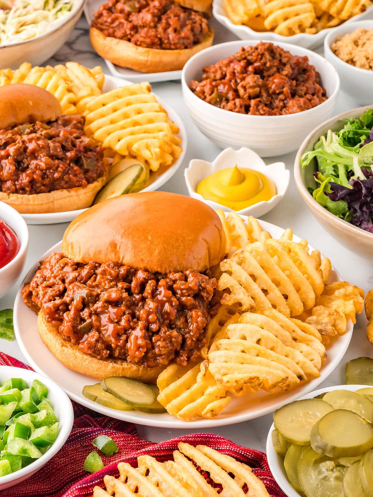 Several plates filled with Sloppy Joes and waffle fries.