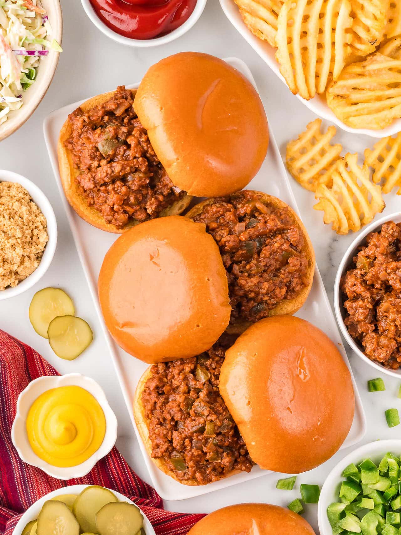A serving plate with several buns filled with homemade Sloppy Joes.