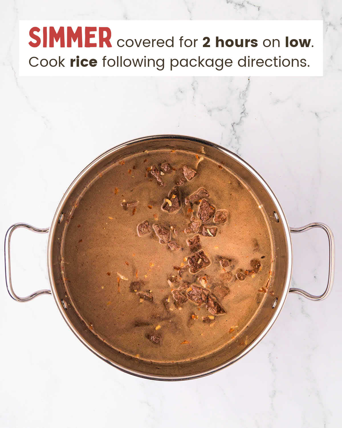 Browned steak pieces covered with broth in a pot.