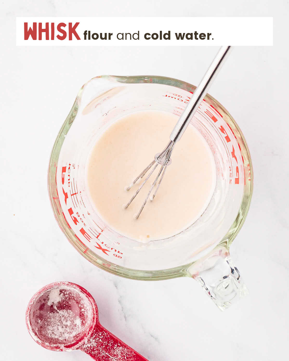 Flour and water mixture with a whisk in a large glass measuring cup.