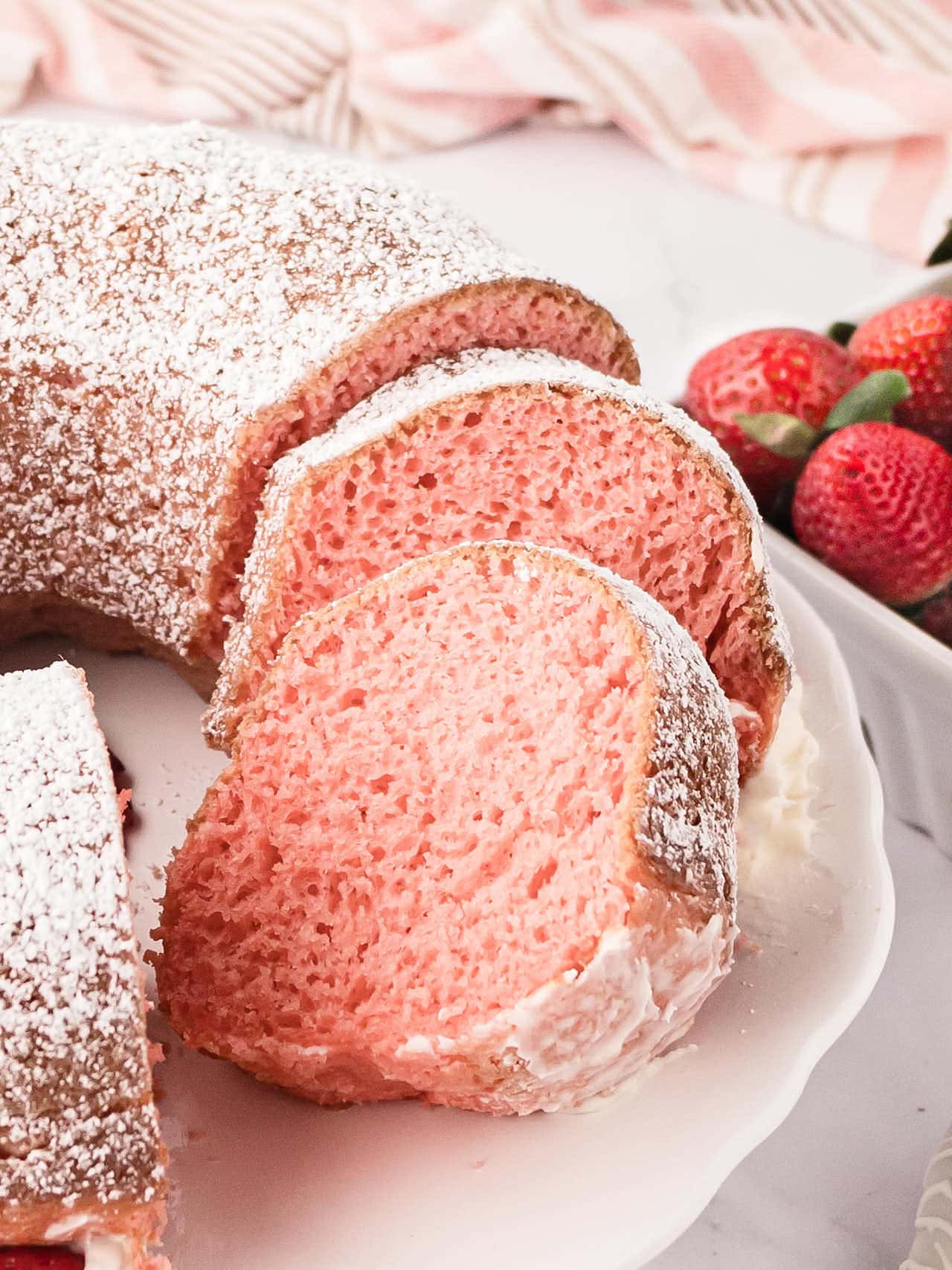 Strawberry Bundt Cake slices on a white cake platter.