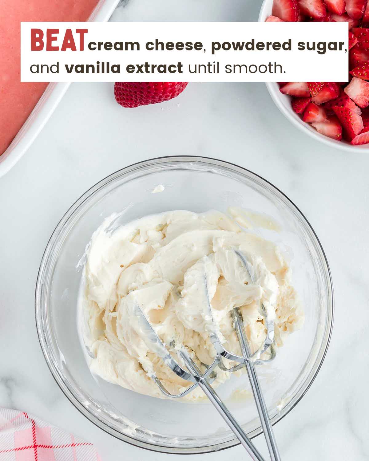 Two beaters in a bowl with cream cheese frosting.