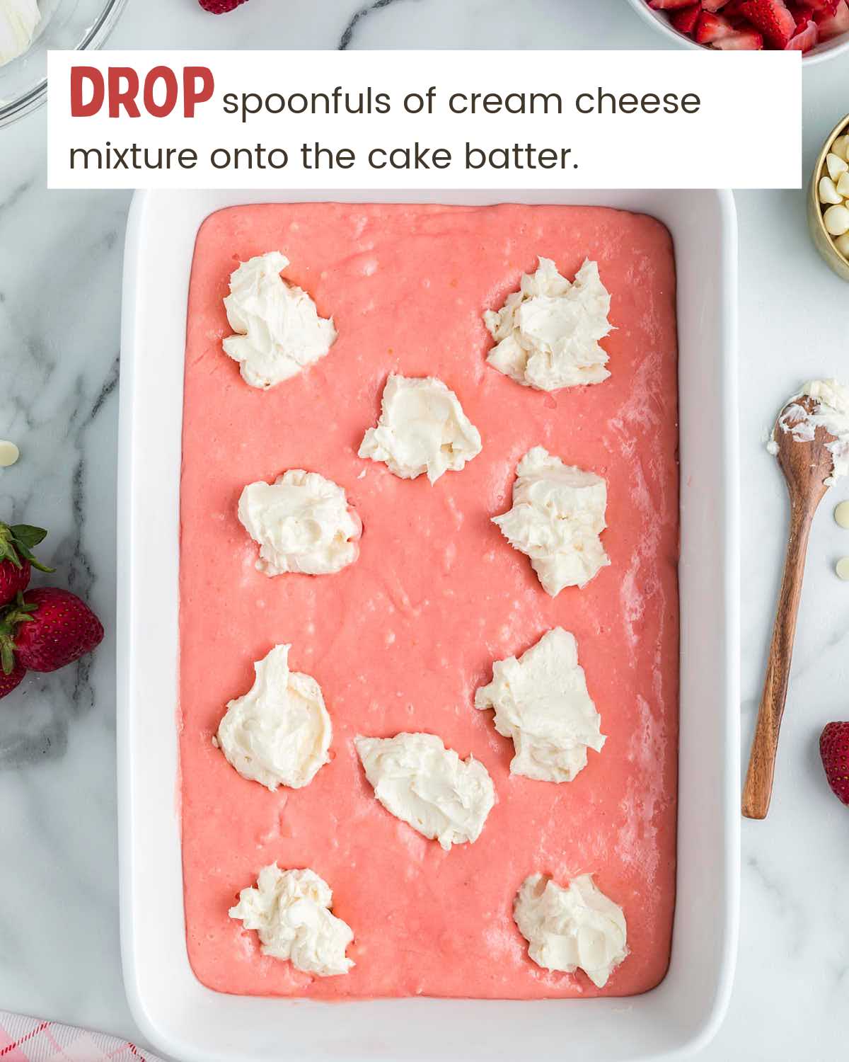 Cream cheese mixture in drops on top of strawberry cake batter in a baking dish.