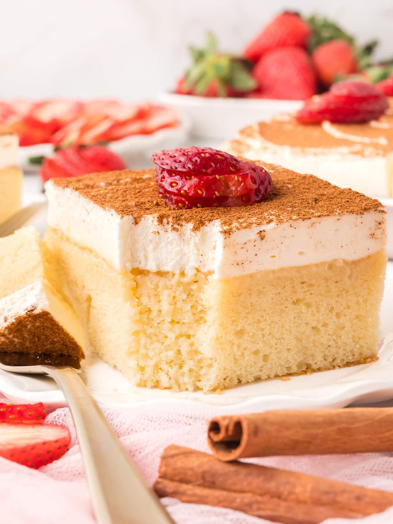 Closeup of a slice of Tres Leche Cake on a white plate. 