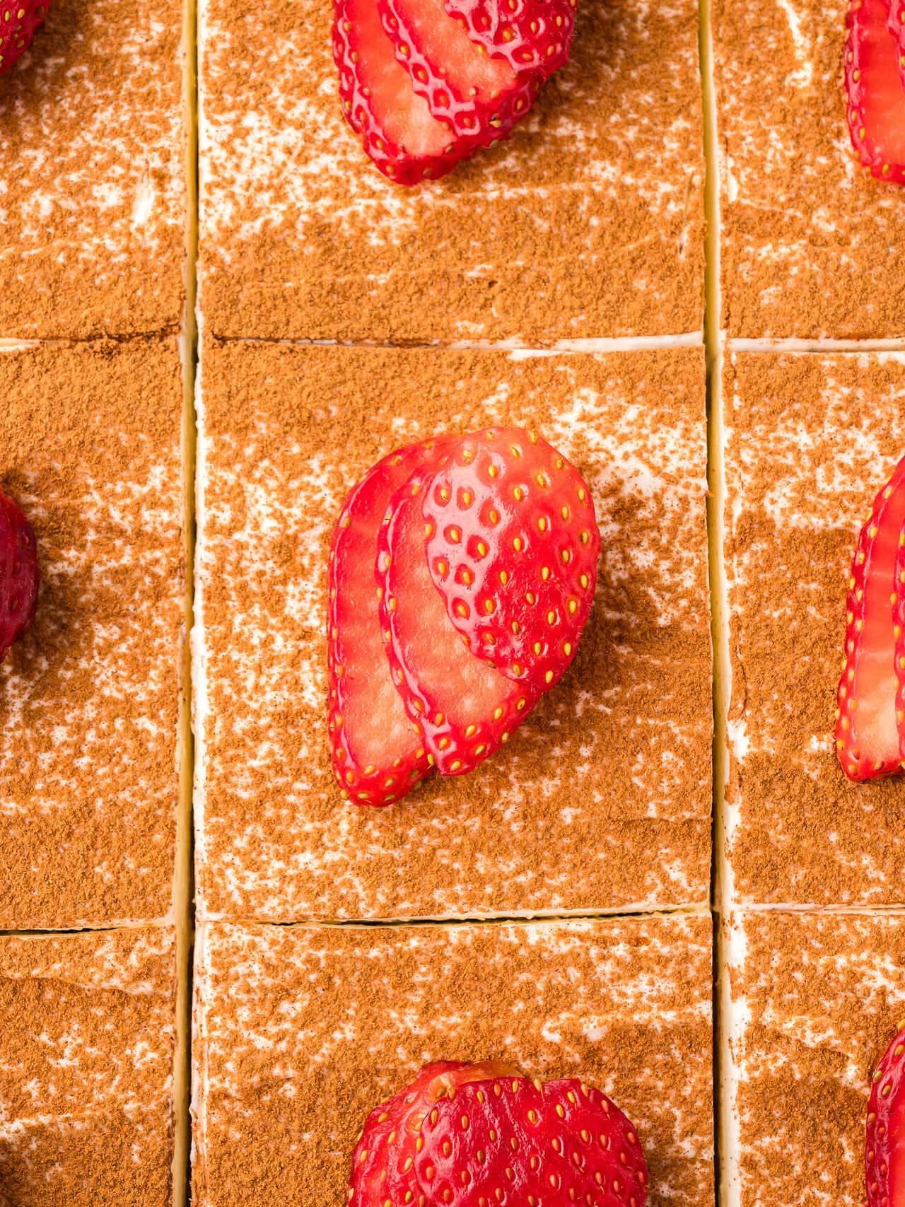 Top down view of a sliced Tres Leches Cake garnished with sliced fresh Strawberries.