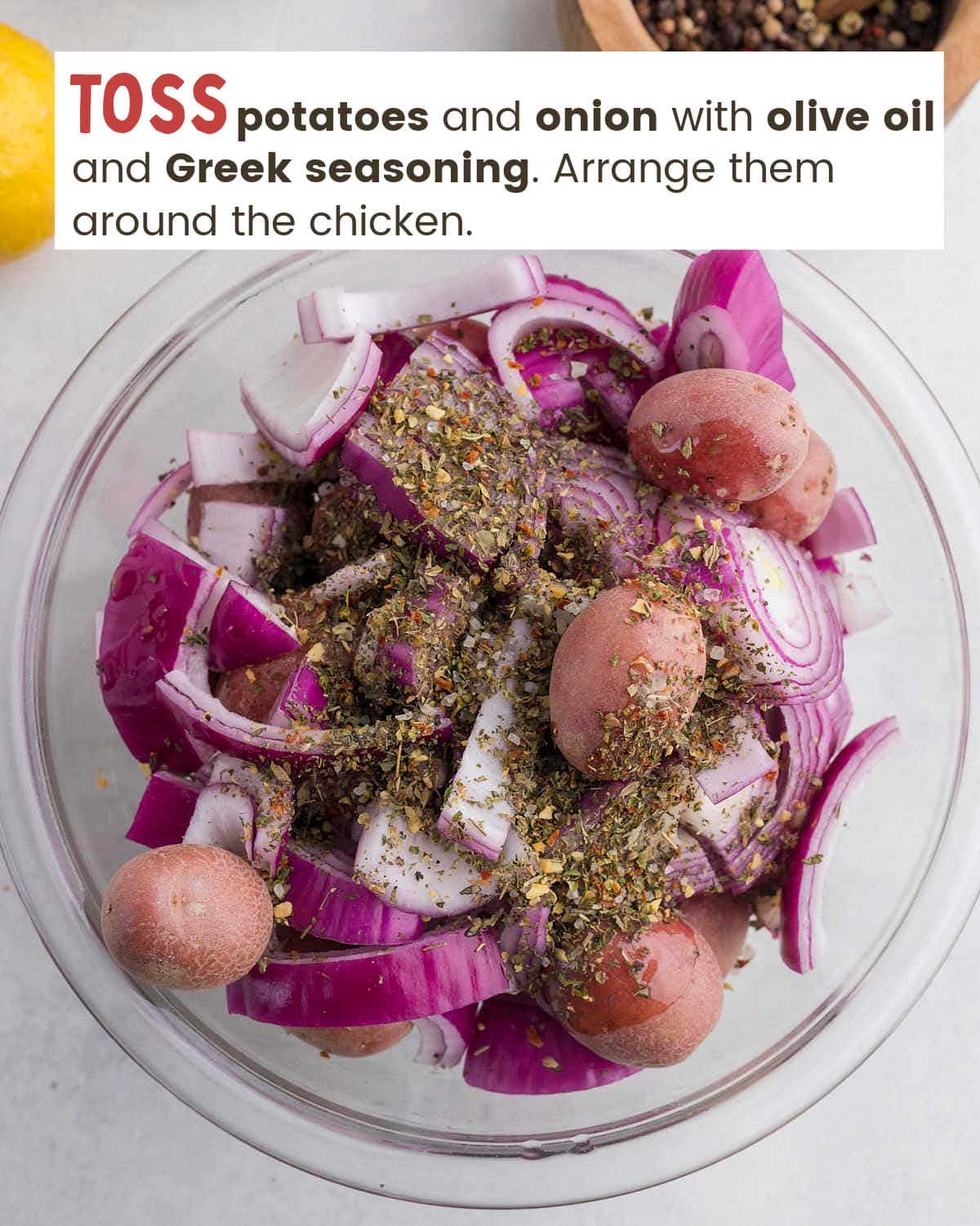 Small potatoes and onion slices topped with seasonings in a mixing bowl.
