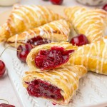 Freshly baked Cherry Turnovers on white serving board.