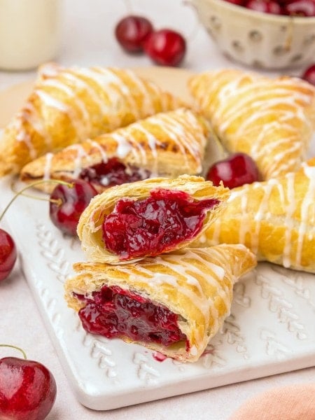 Freshly baked Cherry Turnovers on white serving board.