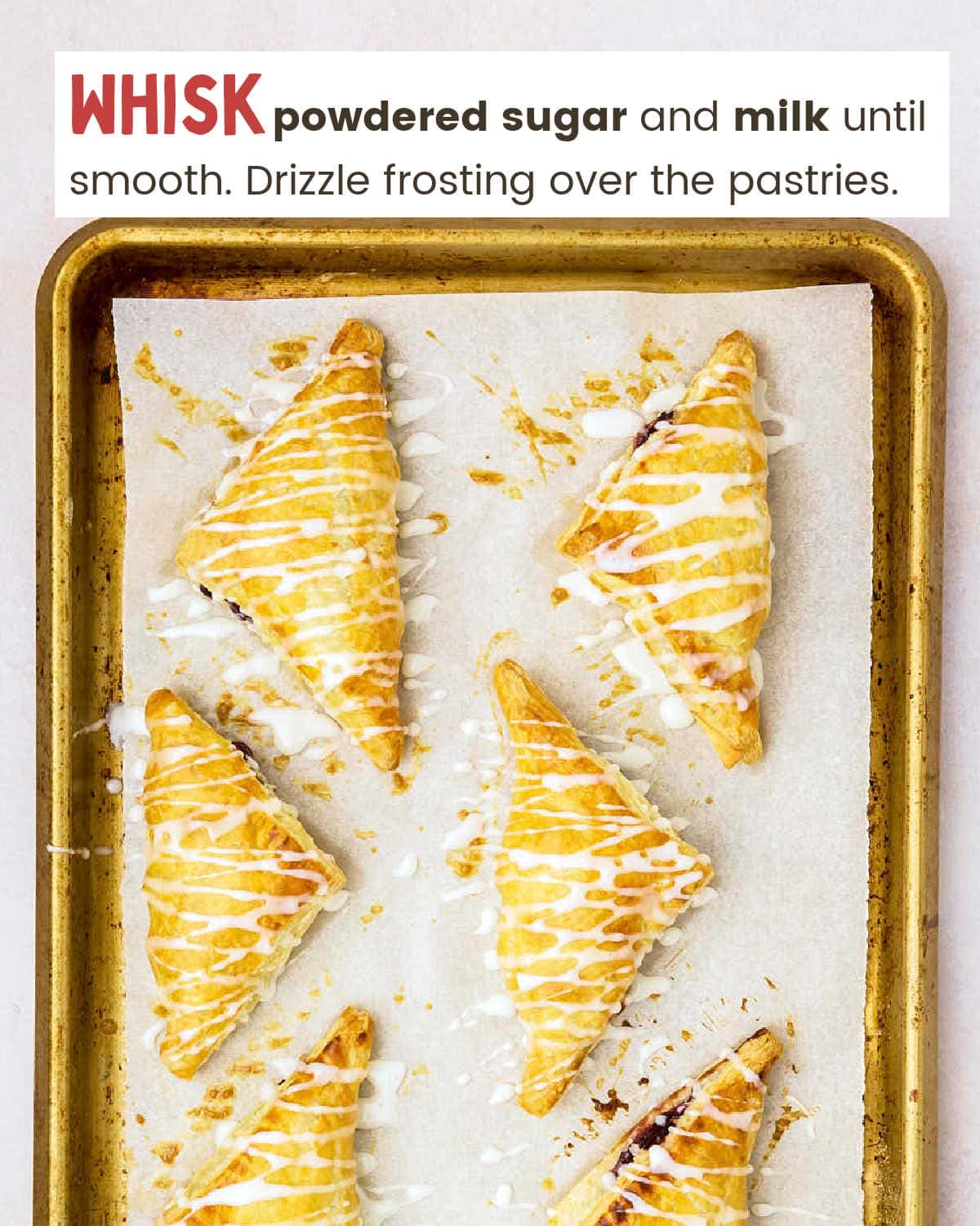 Baked Puff pastry triangles filled with cherry mixture drizzled with frosting on a baking sheet lined with parchment paper.