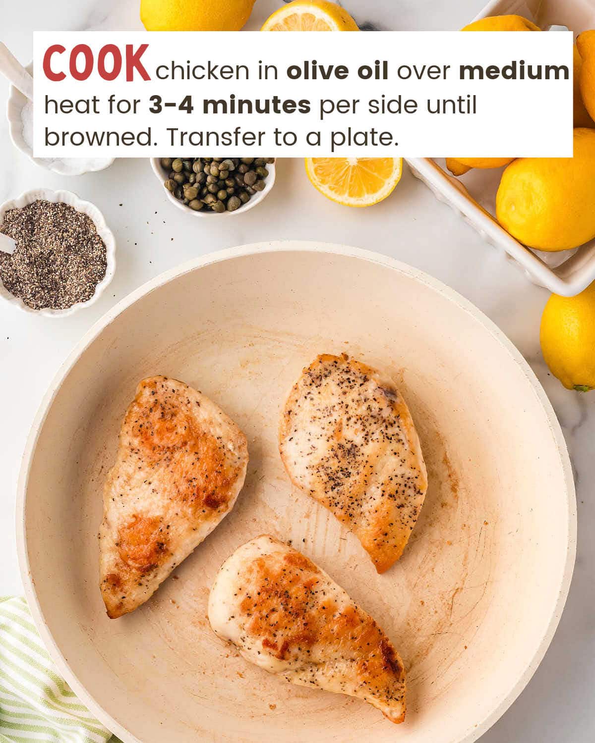 Three browned chicken breasts in a skillet sautéing in olive oil.