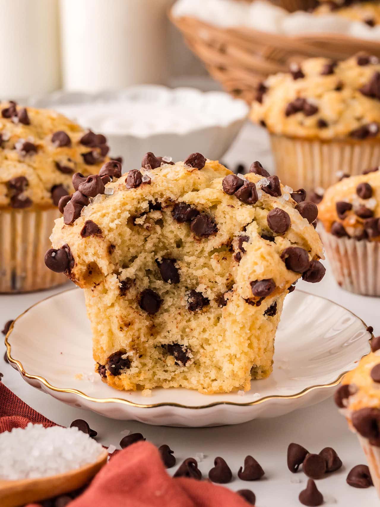 A partially eaten Chocolate Chip Muffins on a white plate.
