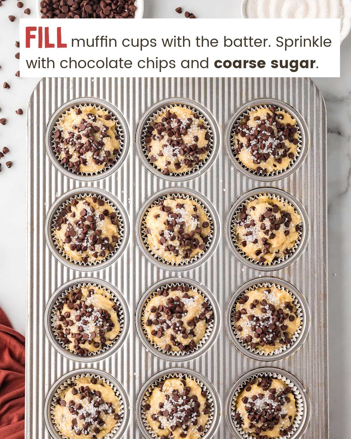 Chocolate chip muffin batter in muffin cups in a muffin tin.
