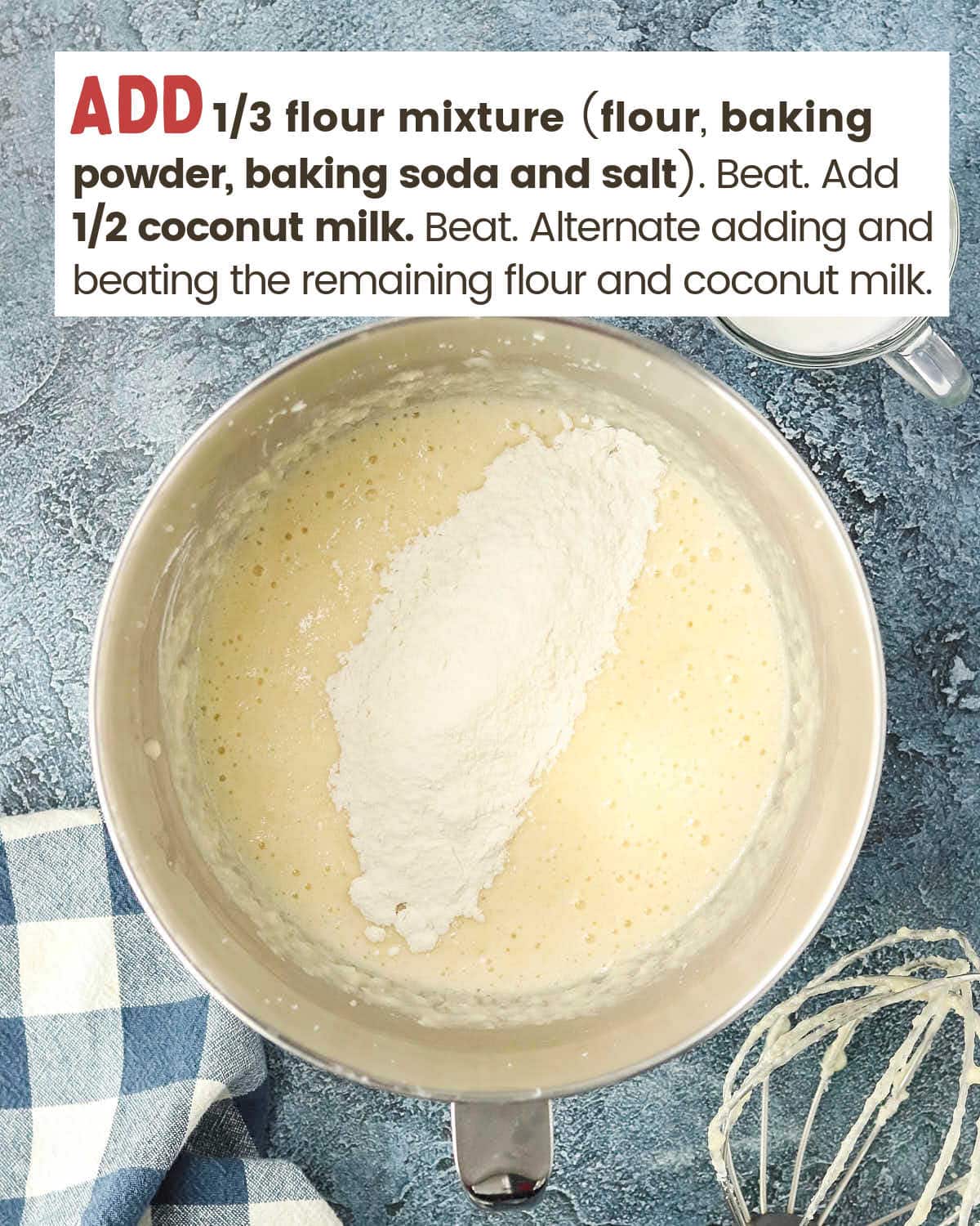 Flour on top of a cake batter mixture in a mixing bowl.