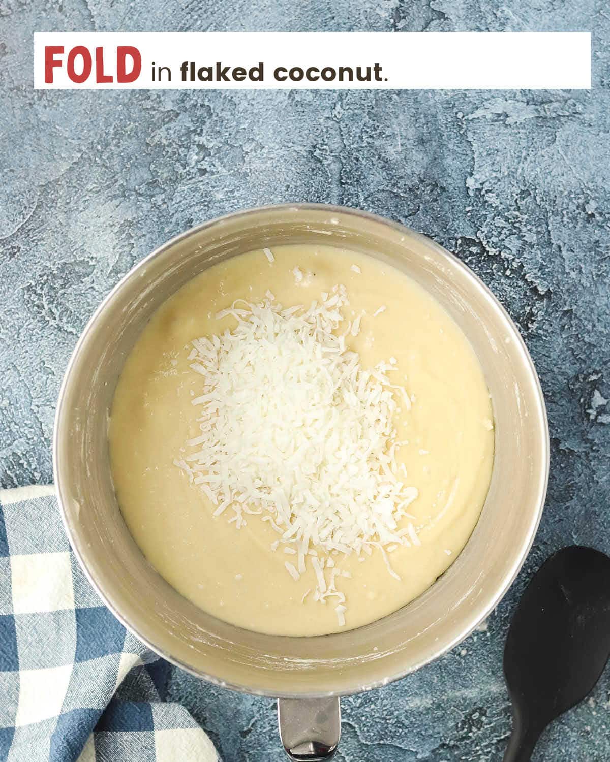 Flaked coconut on top of a cake batter mixture in a mixing bowl.