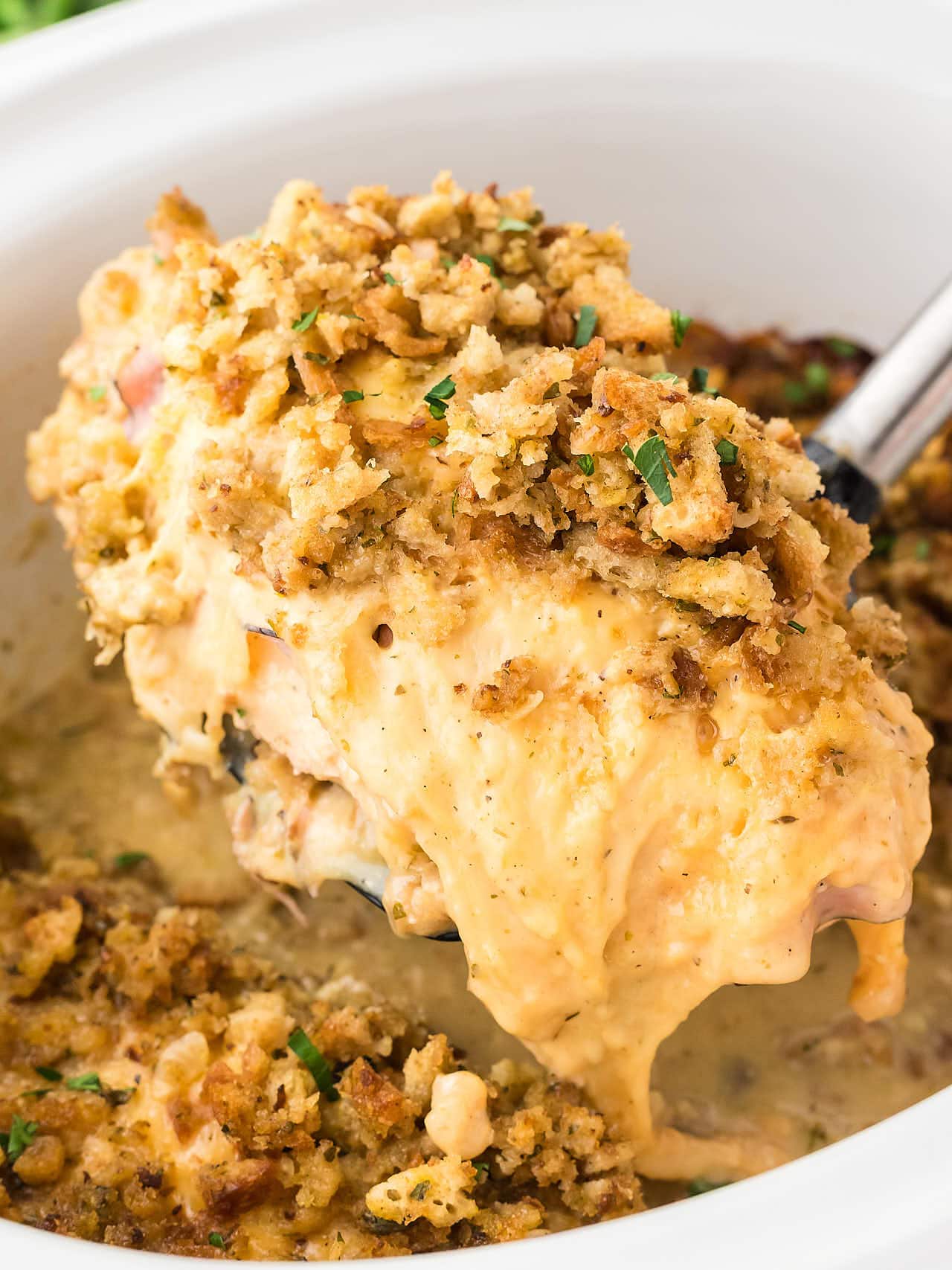 Lifting a slice of Chicken Cordon Bleu out of a slow cooker.