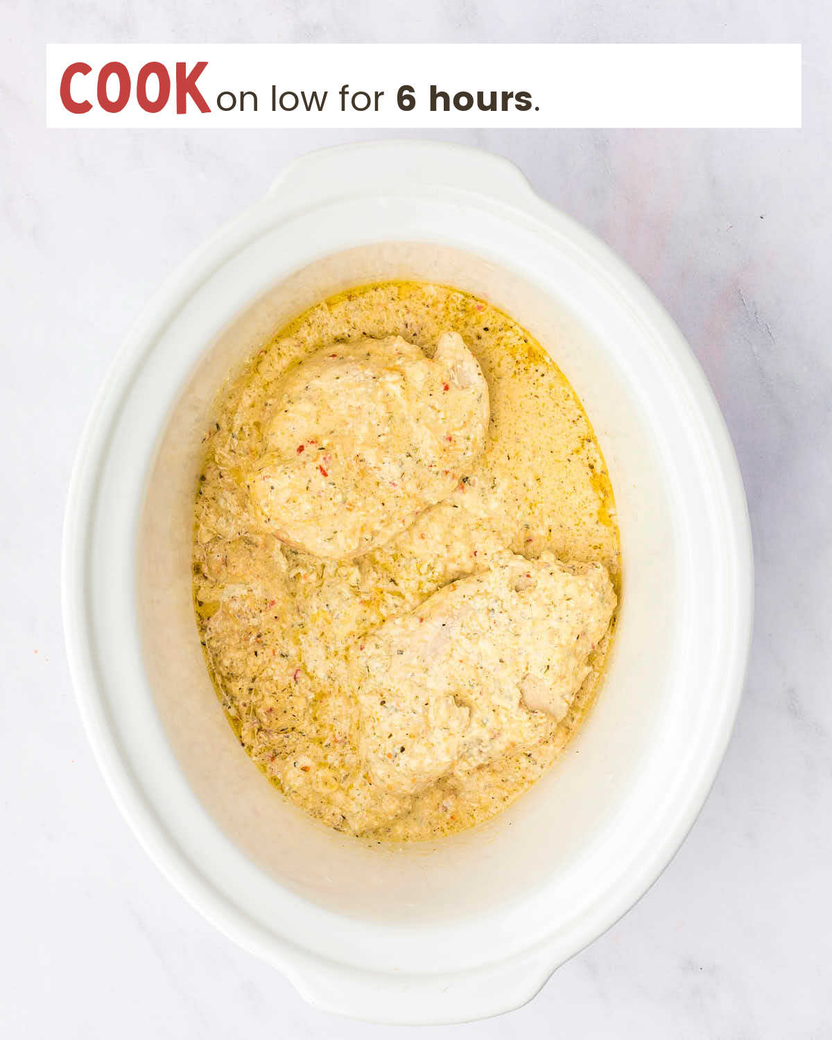 Cooked chicken breasts covered with garlic parmesan sauce in a Crock-Pot.