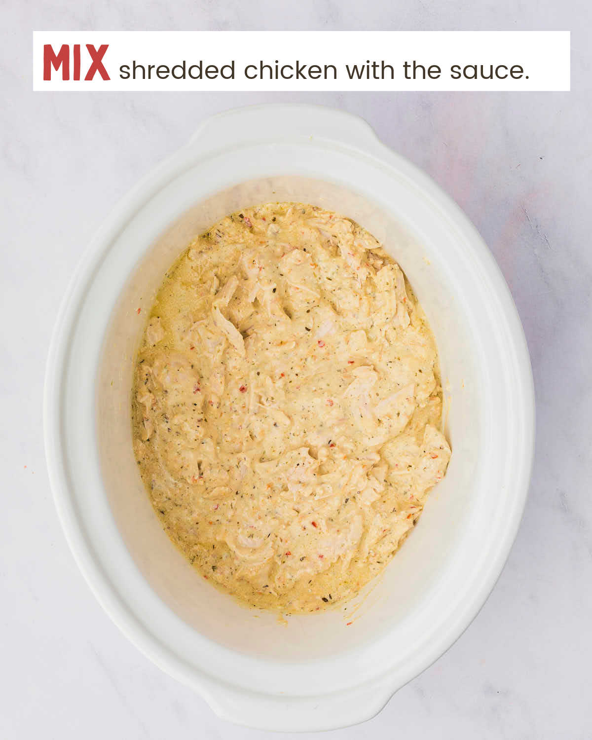 Shredded chicken breasts covered with garlic parmesan sauce in a Crock-Pot.
