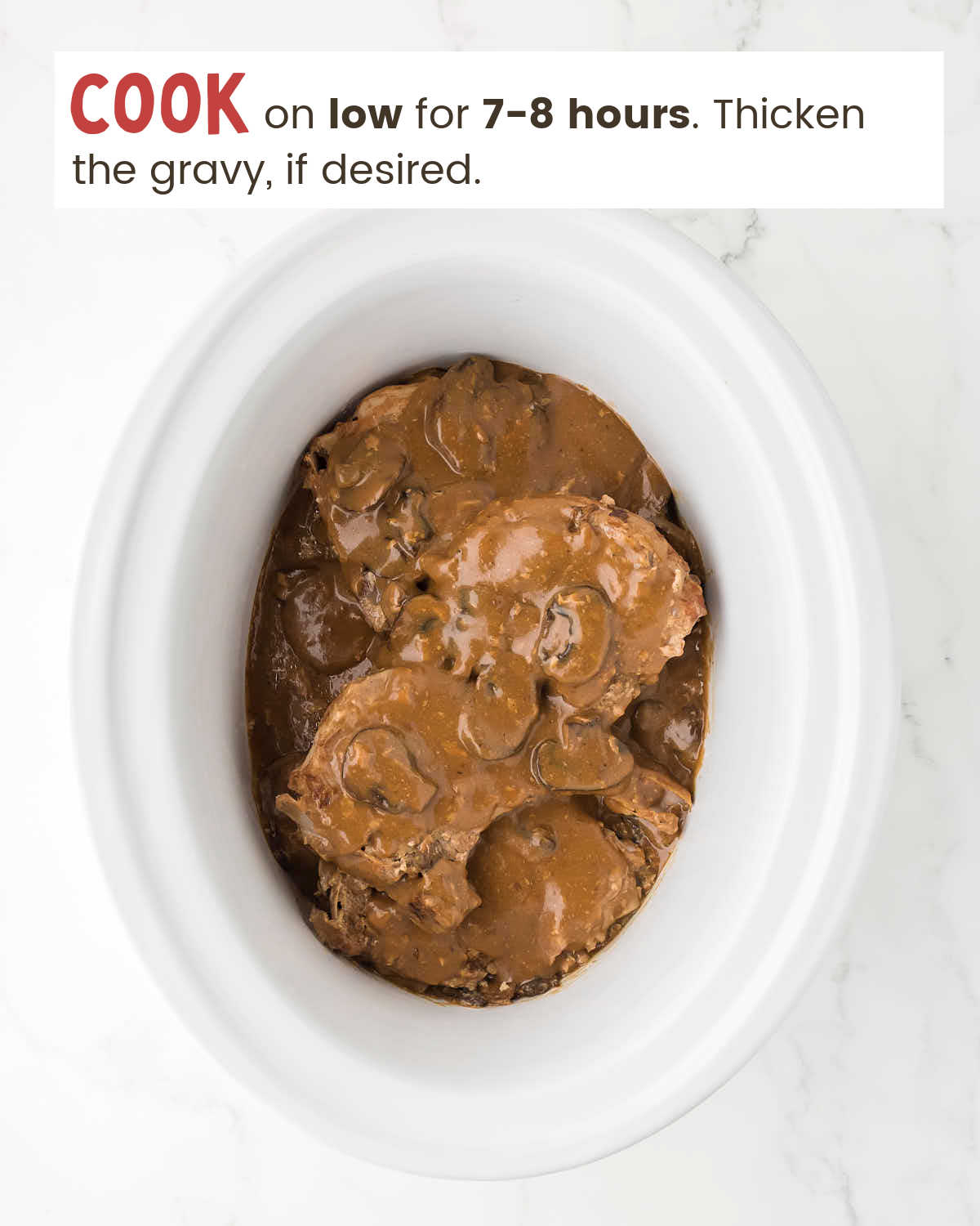 Cooked Pork Chops in a slow cooker covered with gravy.
