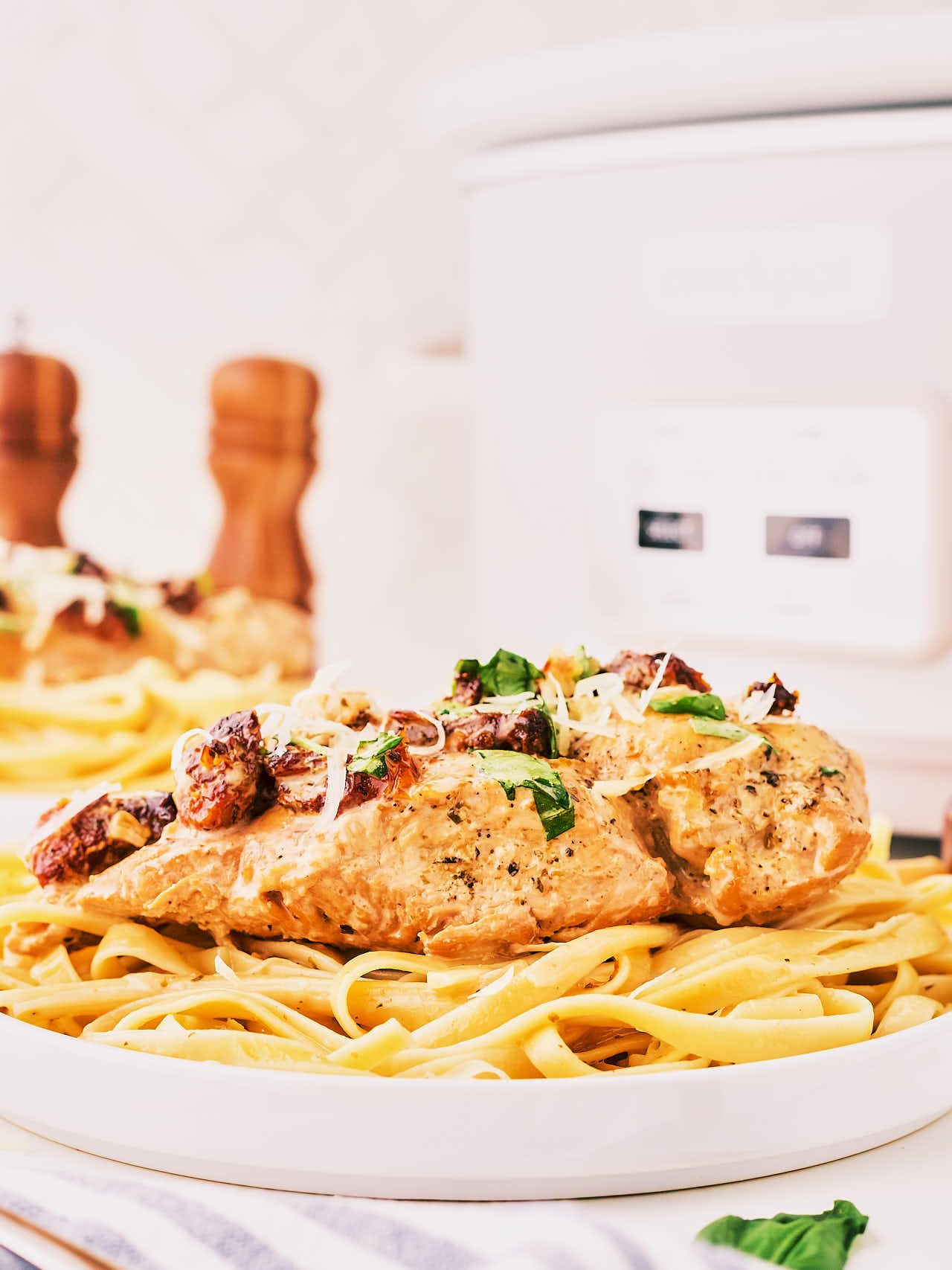 Crockpot Marry Me Chicken served over pasta on a white plate.