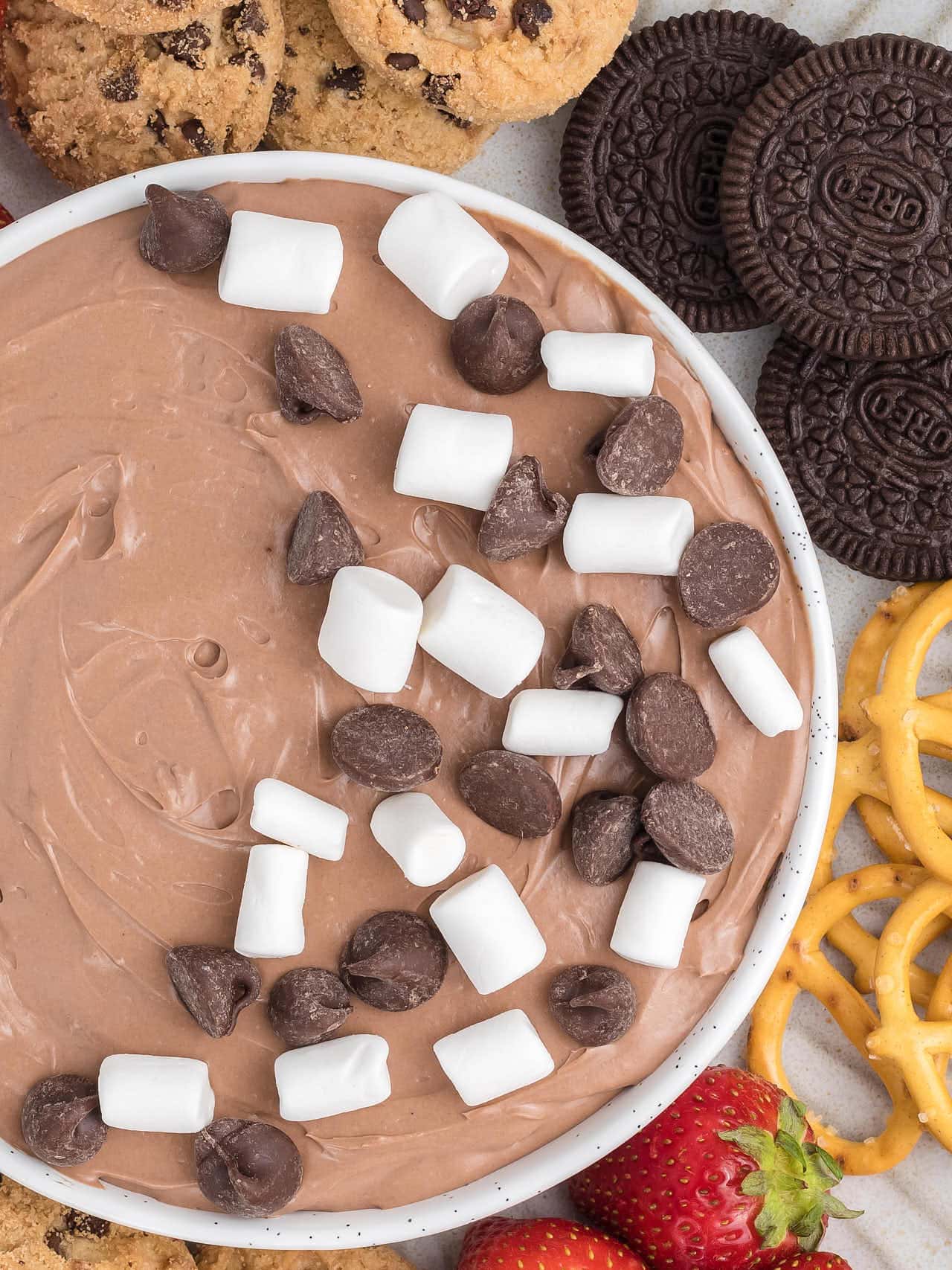 Top down view of a bowl of Hot Chocolate Dip in a white bowl topped with mini marshmallows and chocolate chips. 