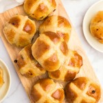 Freshly baked Hot Cross Buns on a wooden plate.