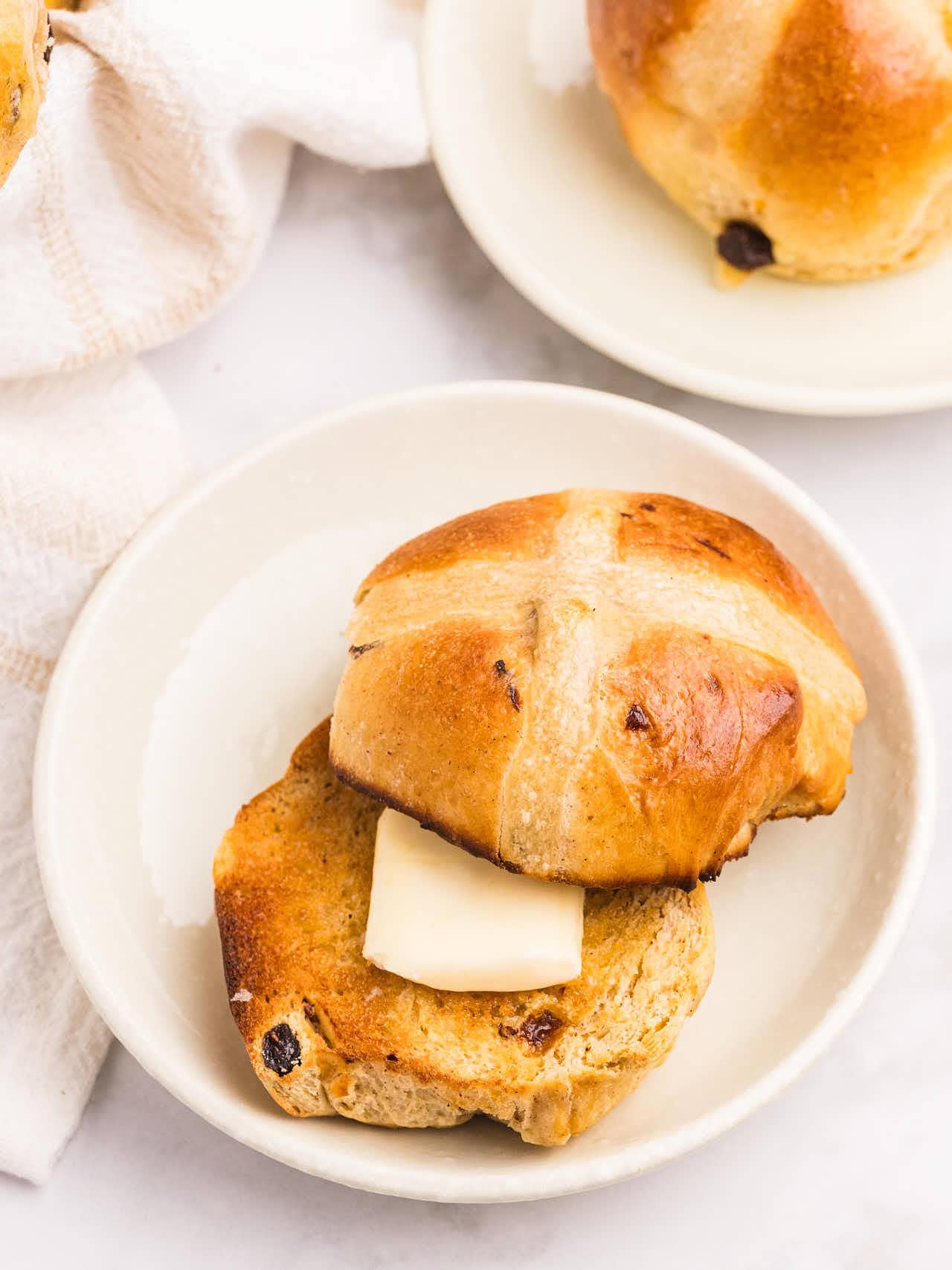 A toasted Hot Cross Bun with a slice of butter.