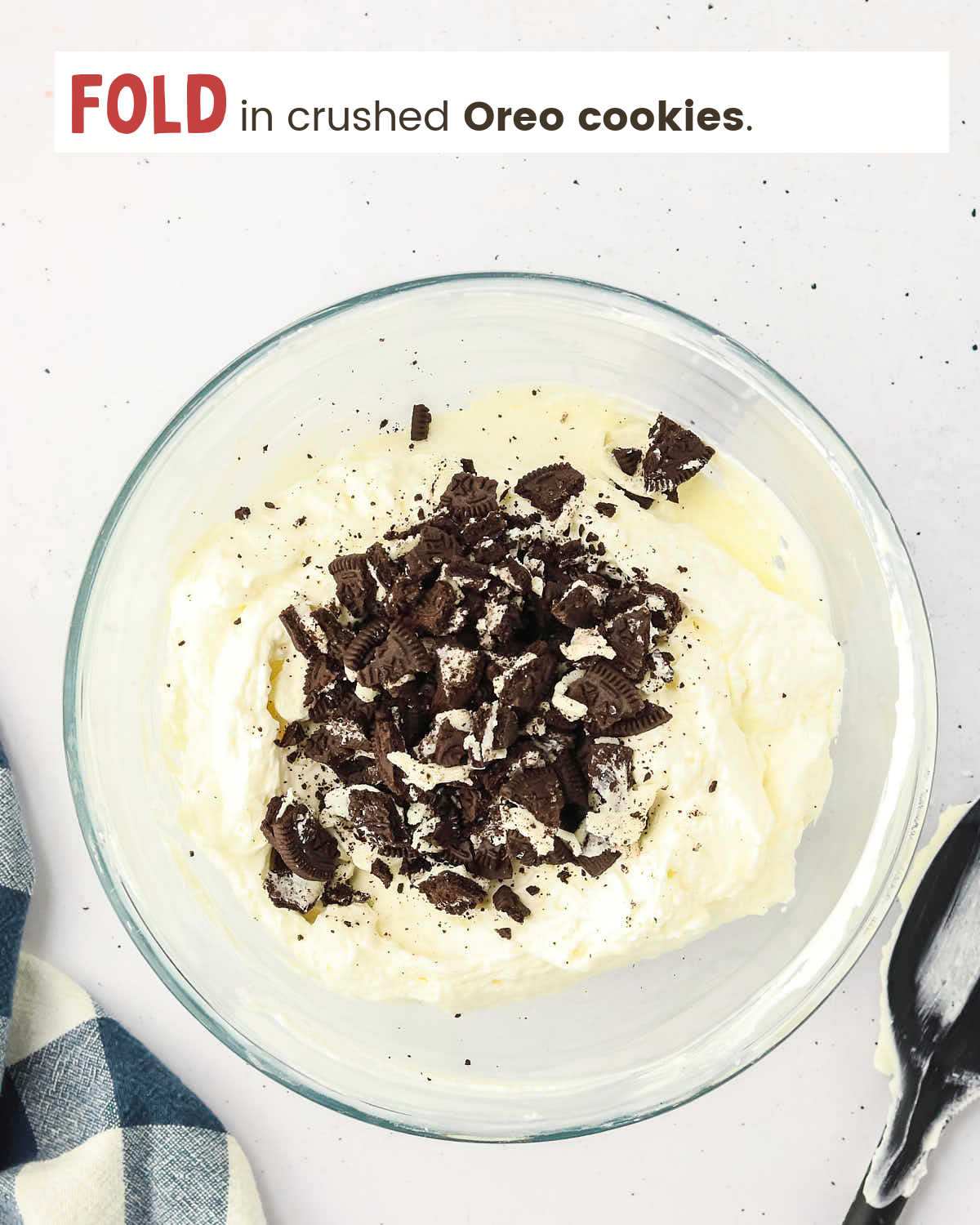 Cream cheese mixture with crushed Oreos on top in a mixing bowl.