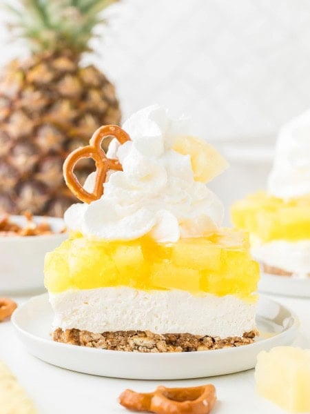 A slice of Pineapple Pretzel Salad topped with whipped cream.