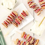 Strawberry Shortcake Kebobs drizzled with white chocolate on plate with whipped cream.