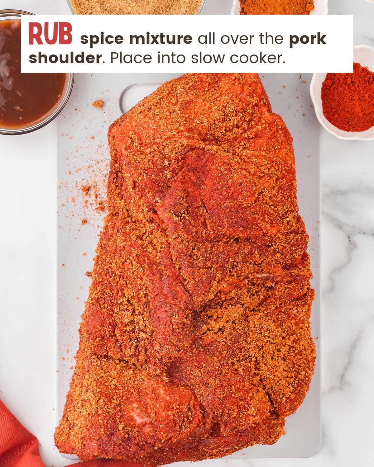Pork shoulder on a cutting board rubbed with spices.