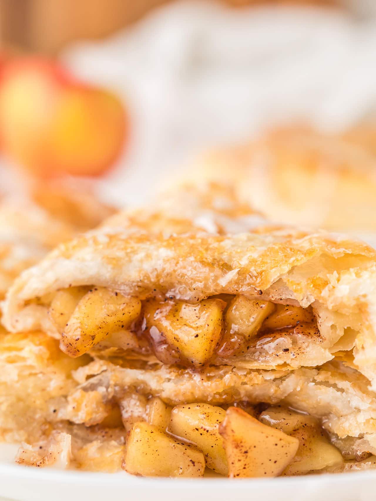 An Apple Turnover sliced in half and stacked on a white plate.