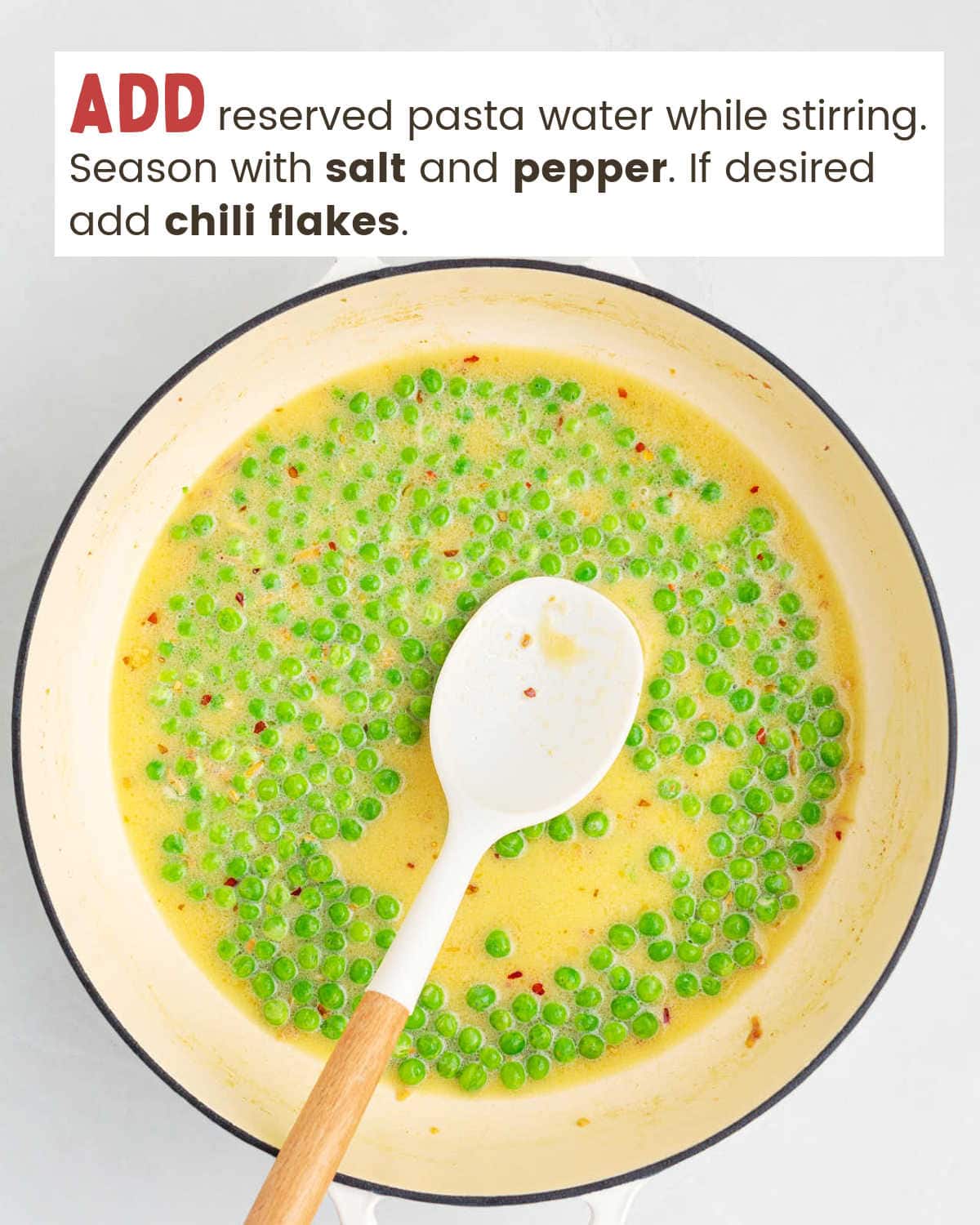 A spatula in a pan with frozen peas and pasta water.