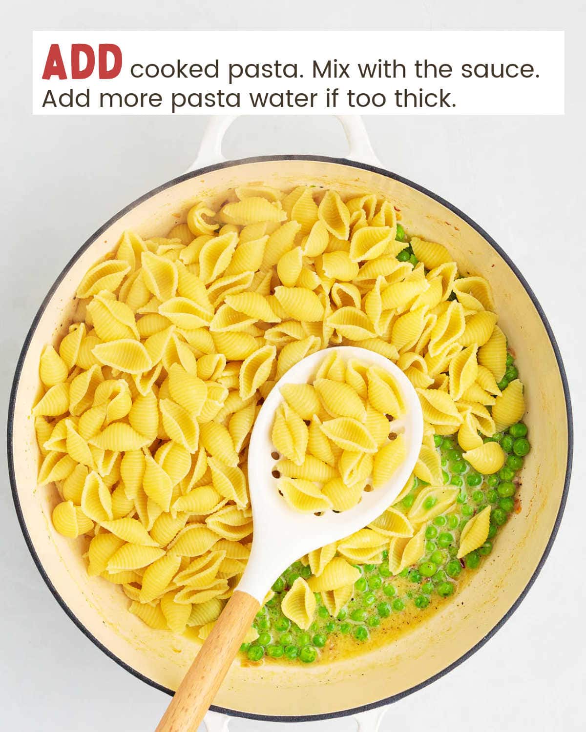 Cooked pasta and frozen peas in a pan with a large spoon holding some of the cooked pasta.