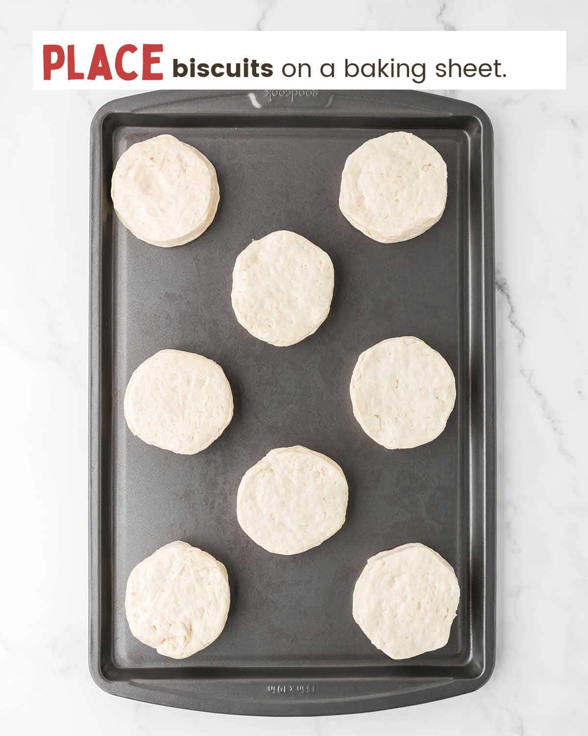 Raw canned biscuits on a baking sheet.