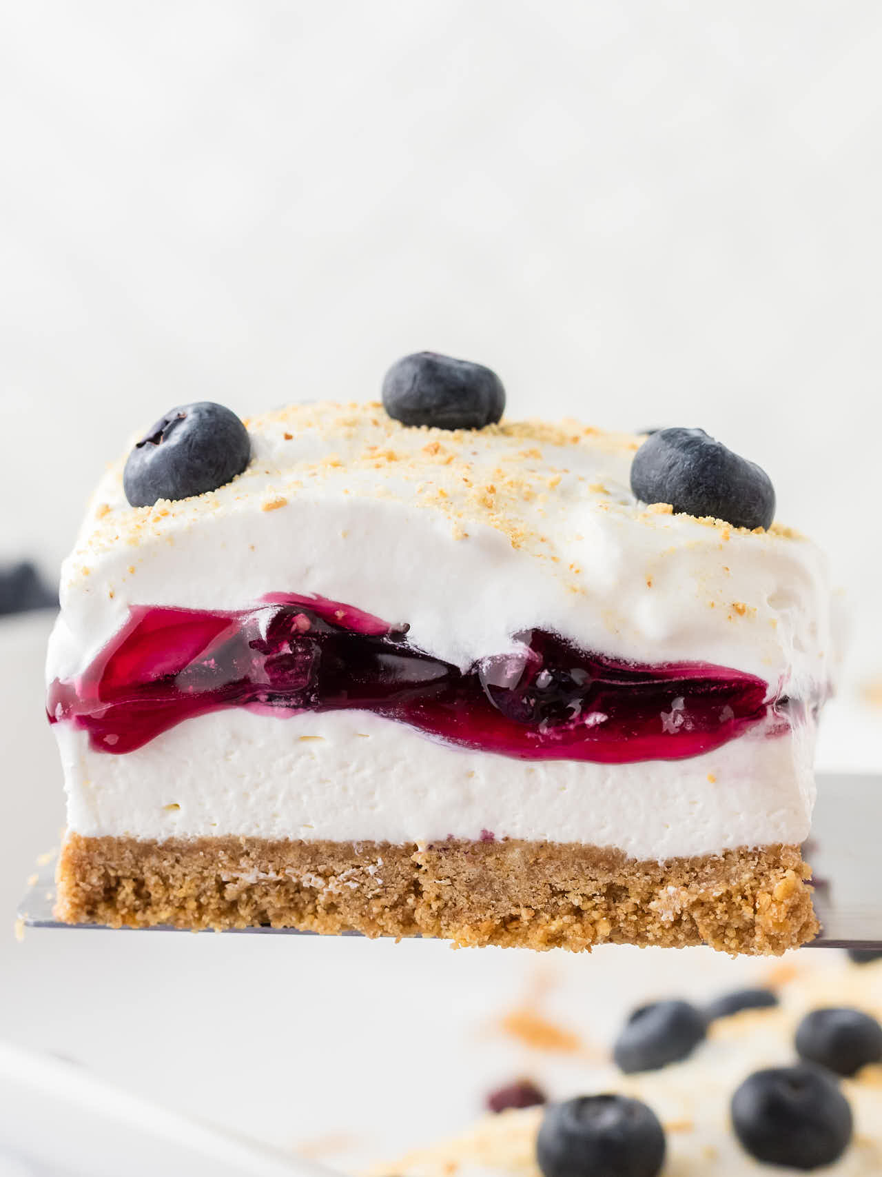 Lifting a slice of Blueberry Delight out of a baking dish.