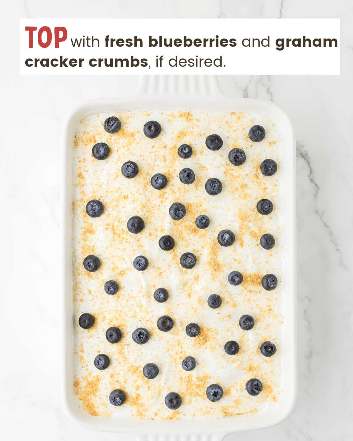 Blueberry delight topped with fresh blueberries and graham cracker crumbs in a baking dish.