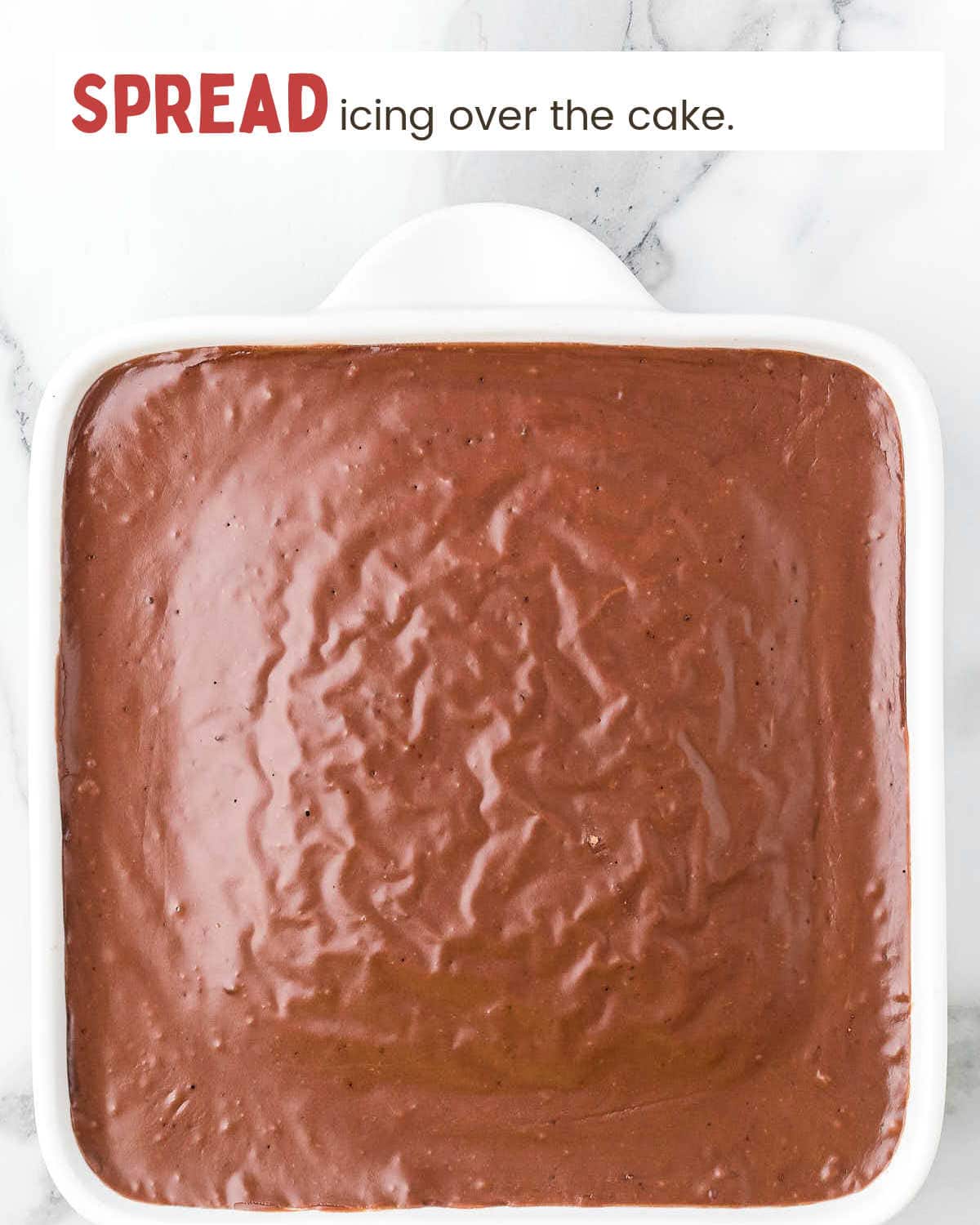 Chocolate icing covers a chocolate cake in a baking dish.