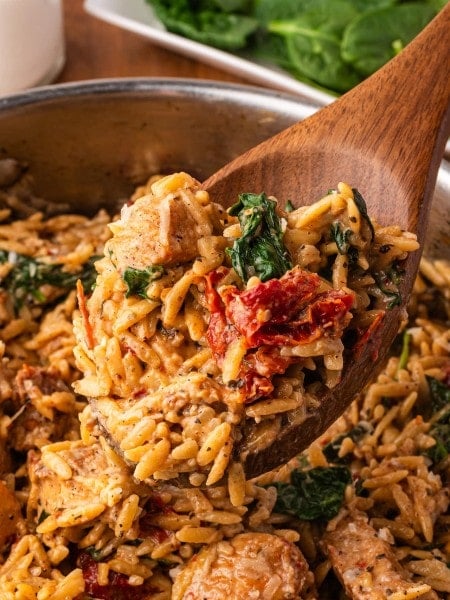 A wooden serving spoon filled with Marry Me Chicken Orzo.