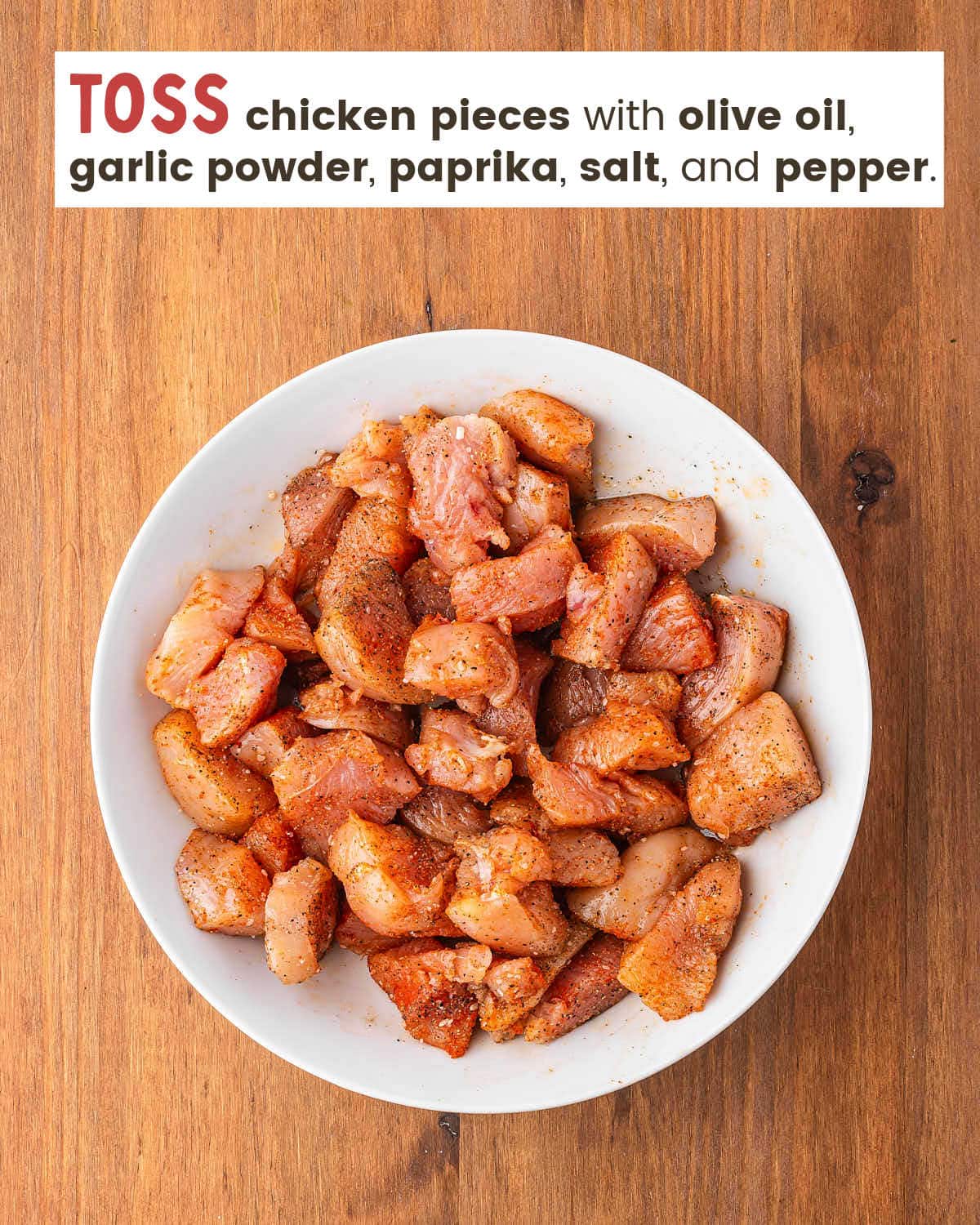 Chicken breast pieces coated with olive oil and seasonings in a white bowl. 