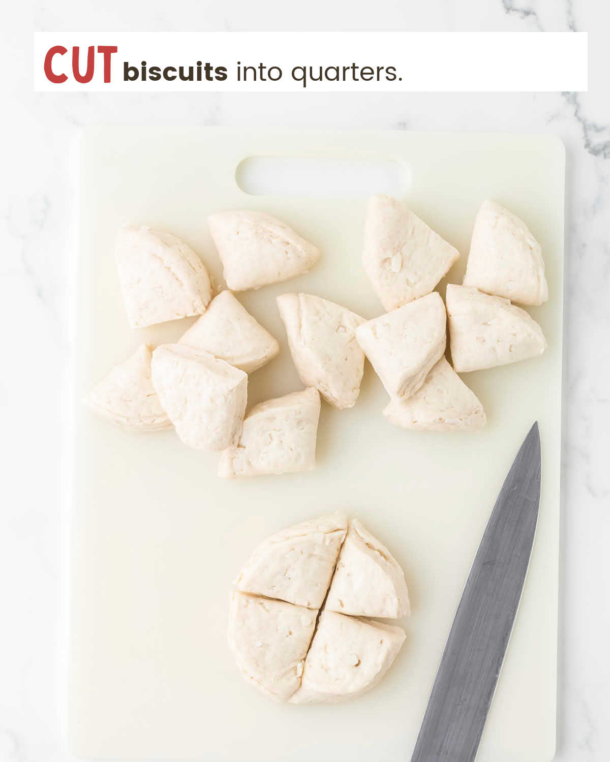 Round raw biscuits cut into quarters on a cutting board. A knife is next to the biscuits. 