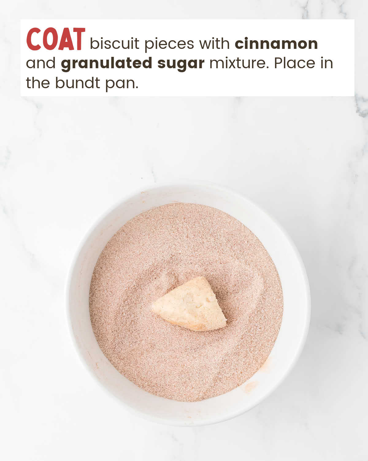 A biscuit piece on top of a cinnamon and sugar mixture in a white bowl.