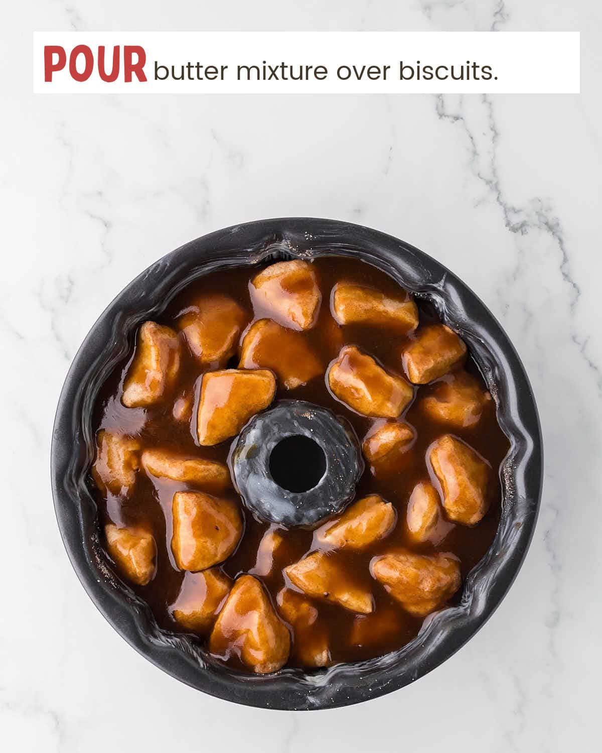 Melted butter mixture covers biscuit pieces in a Bundt pan.