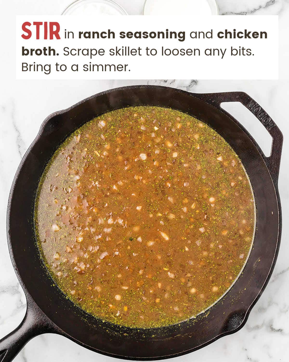 Chicken broth mixture in a cast iron skillet.