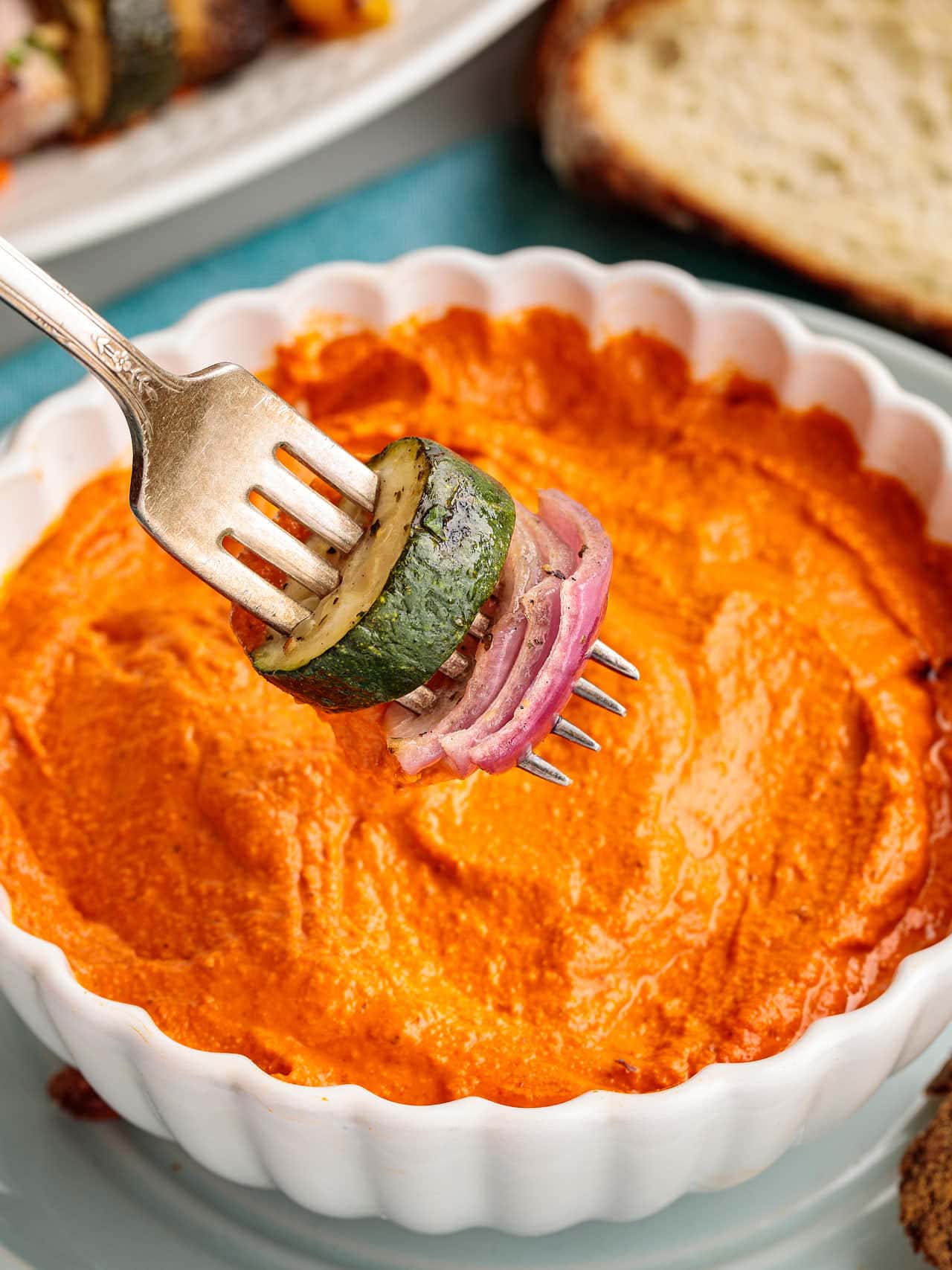 A forkful of roasted vegetables dipped into Romesco sauce.