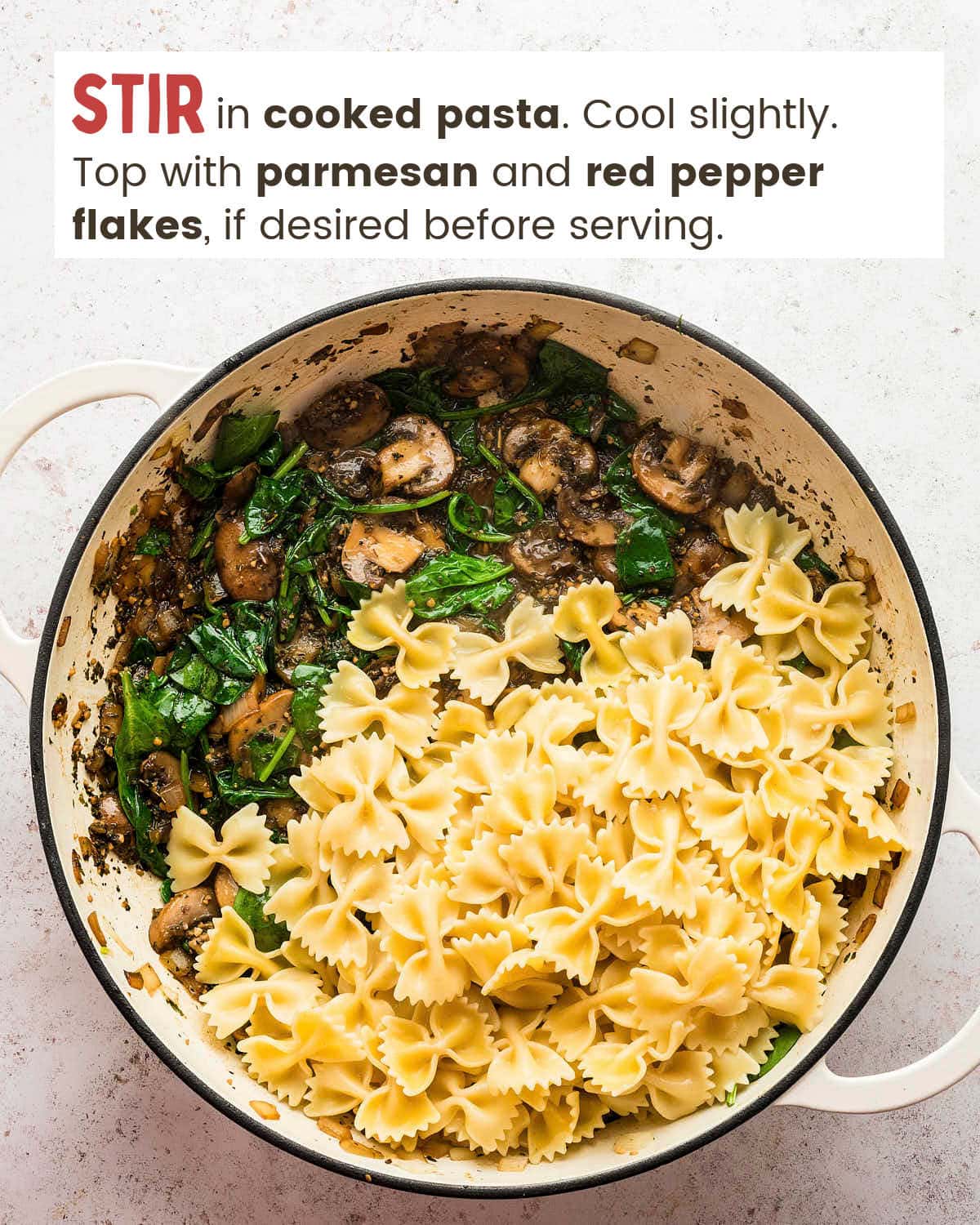 Wilted spinach in a mushroom sauce topped with cooked pasta in a pot. 