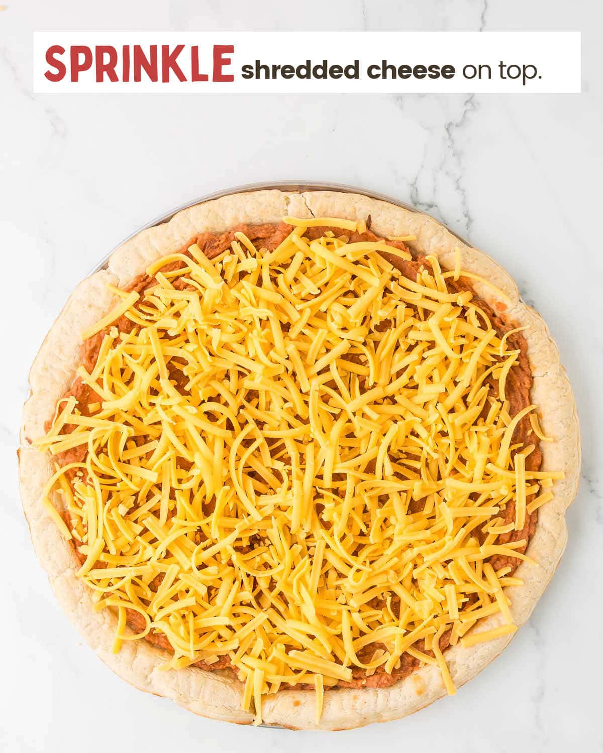 Refried bean mixture spread over pizza crust topped with cheese.