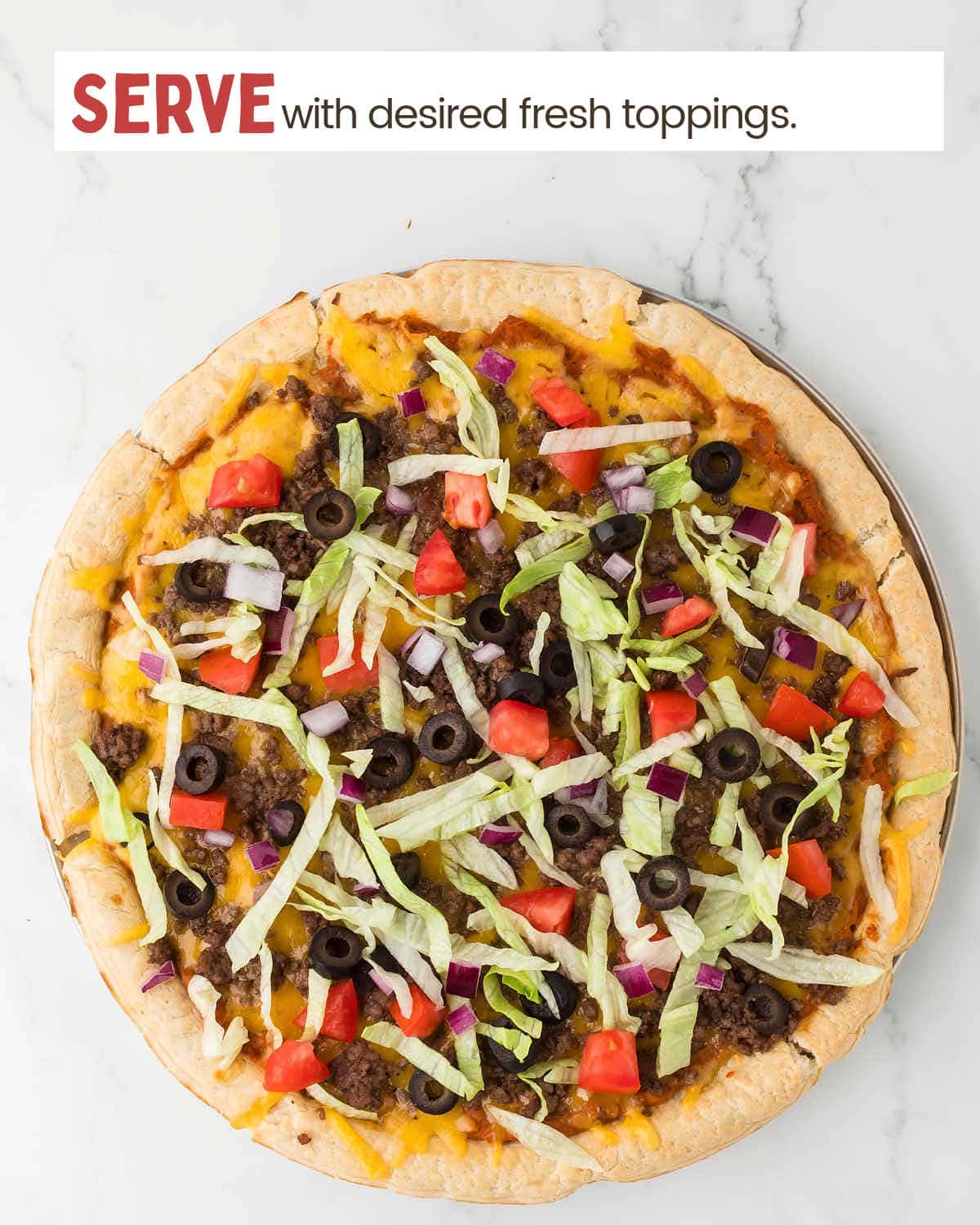 Taco pizza topped with fresh ingredients like black olives, lettuce, and tomatoes.